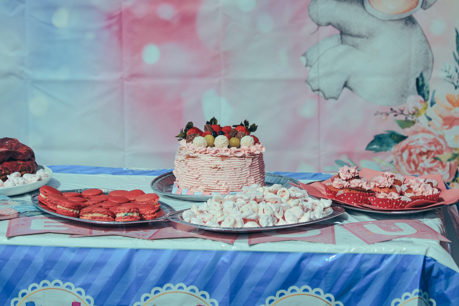 Vibrant dessert table featuring a cake with strawberries and assorted sweets, perfect for celebrations.