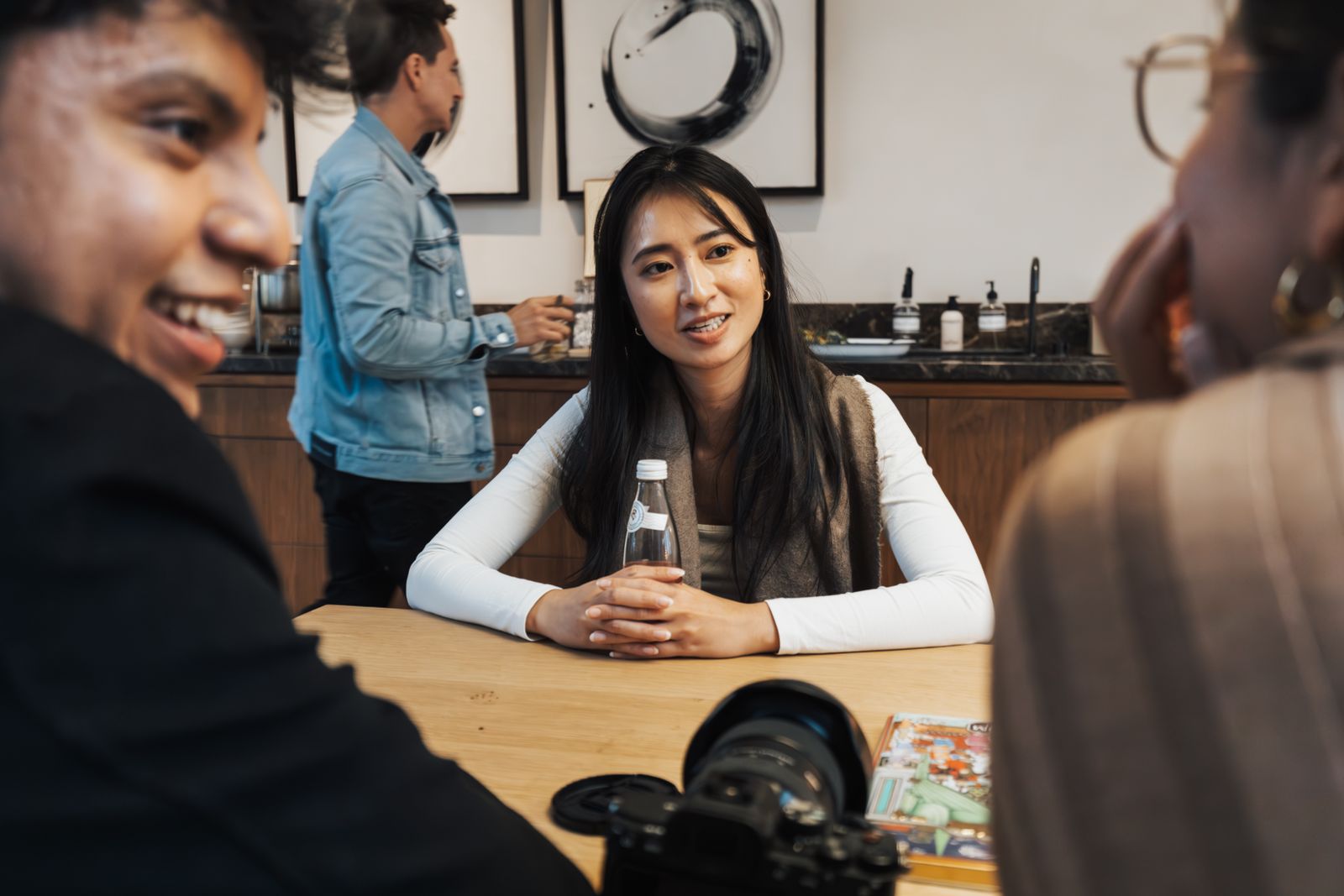 A group of young adults socializing in a modern cafe setting, captured candidly.