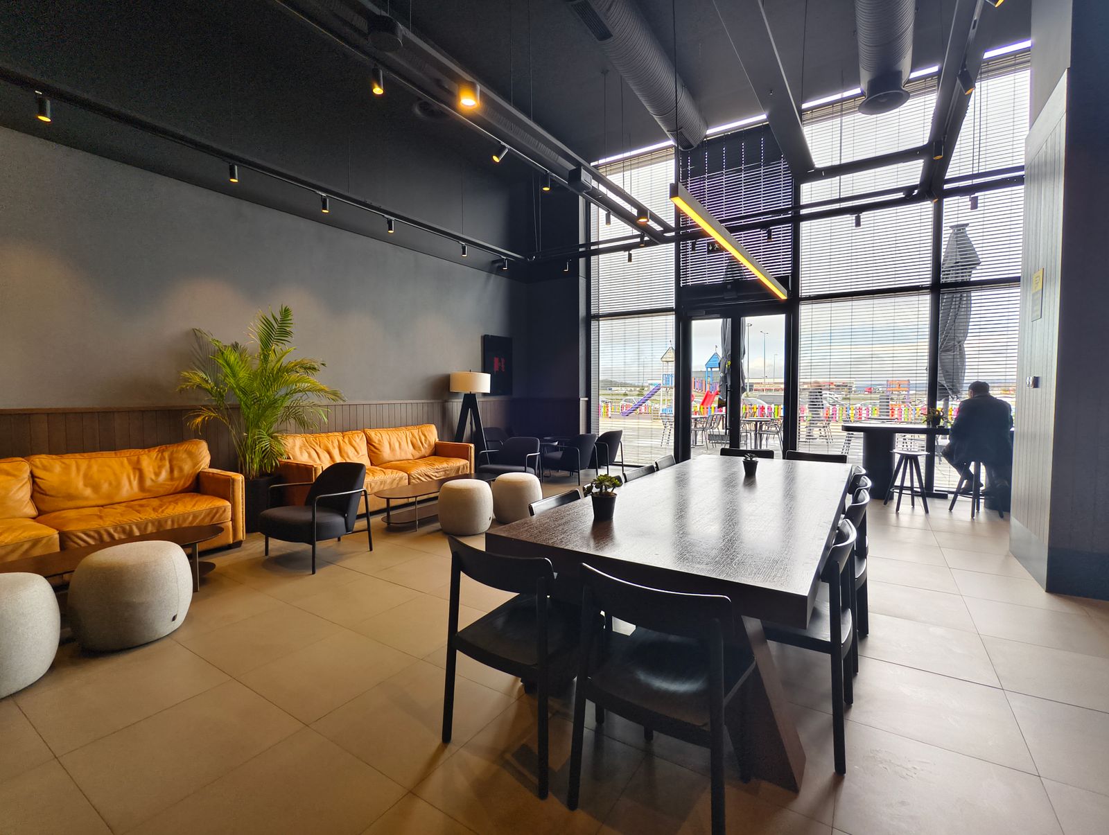 Spacious and stylish lounge area in a contemporary cafe with large windows and comfortable seating.